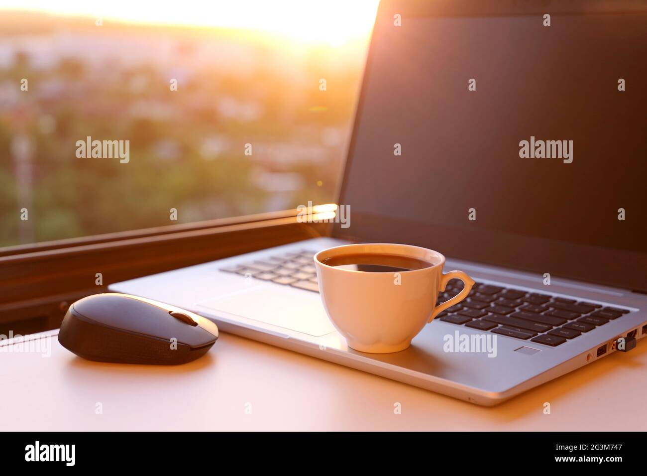 Tazza di caffè calda e computer portatile sul tavolo contro la finestra al  tramonto. Ambiente di lavoro accogliente in ufficio domestico, concetto di  lavoro remoto e guadagnare online Foto stock - Alamy