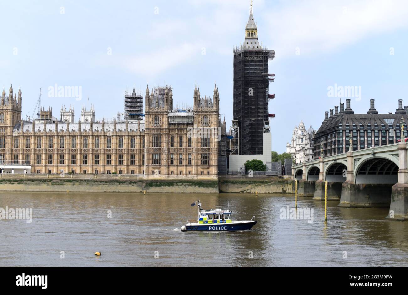 Una barca di polizia passa lungo il Tamigi passando per il Palazzo di Westminster in un caldo e luminoso giorno di giugno Foto Stock
