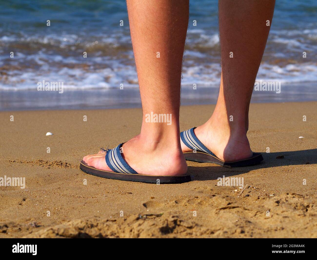 uomo che indossa le ciabatte in piedi sulla spiaggia Foto stock - Alamy