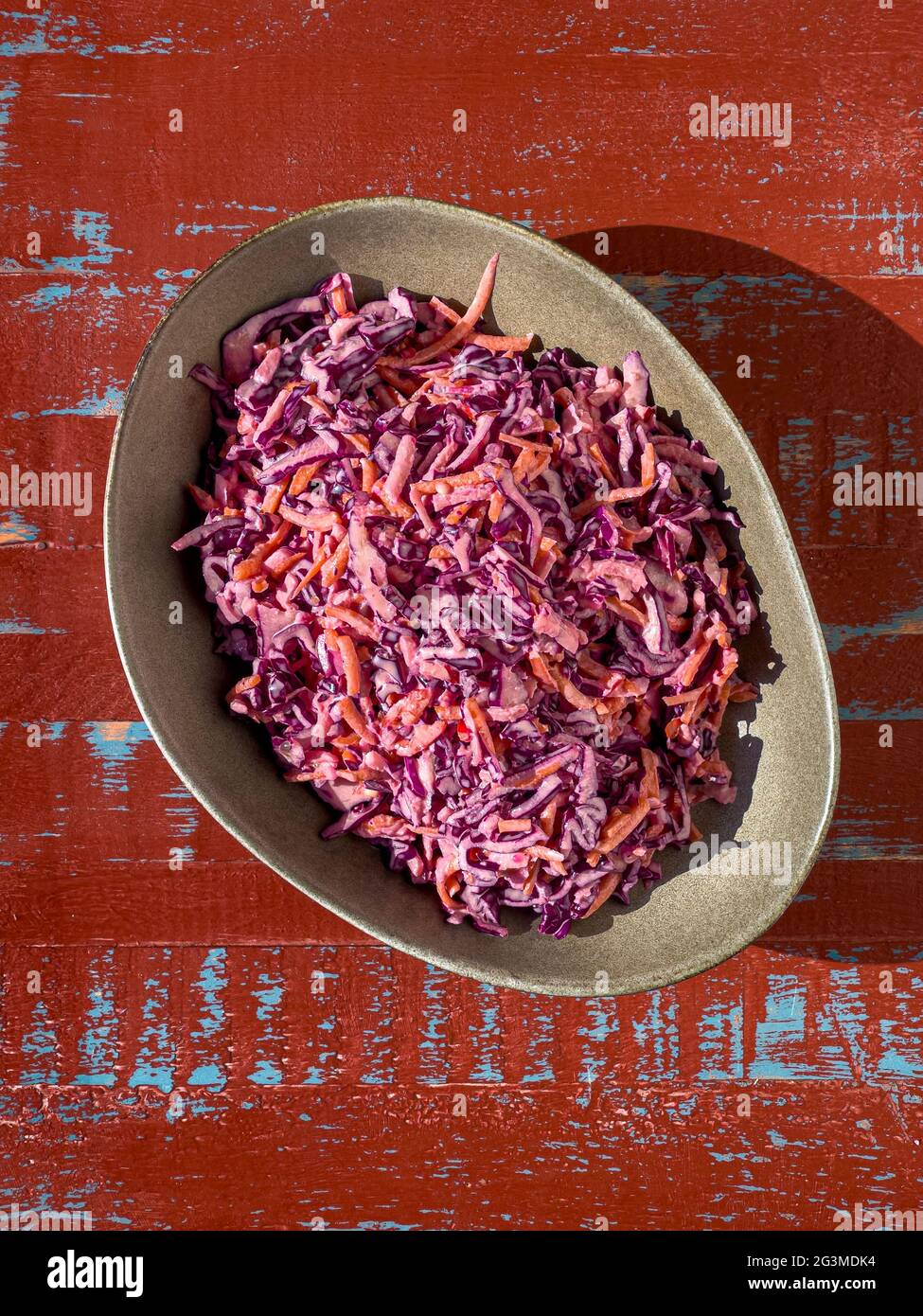 Ciotola di coleslaw appena fatto su uno sfondo rustico marrone e blu, sparato dall'alto. Foto Stock