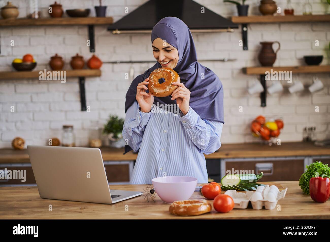 Giovane araba che ha una videochiamata sul suo laptop in cucina Foto Stock