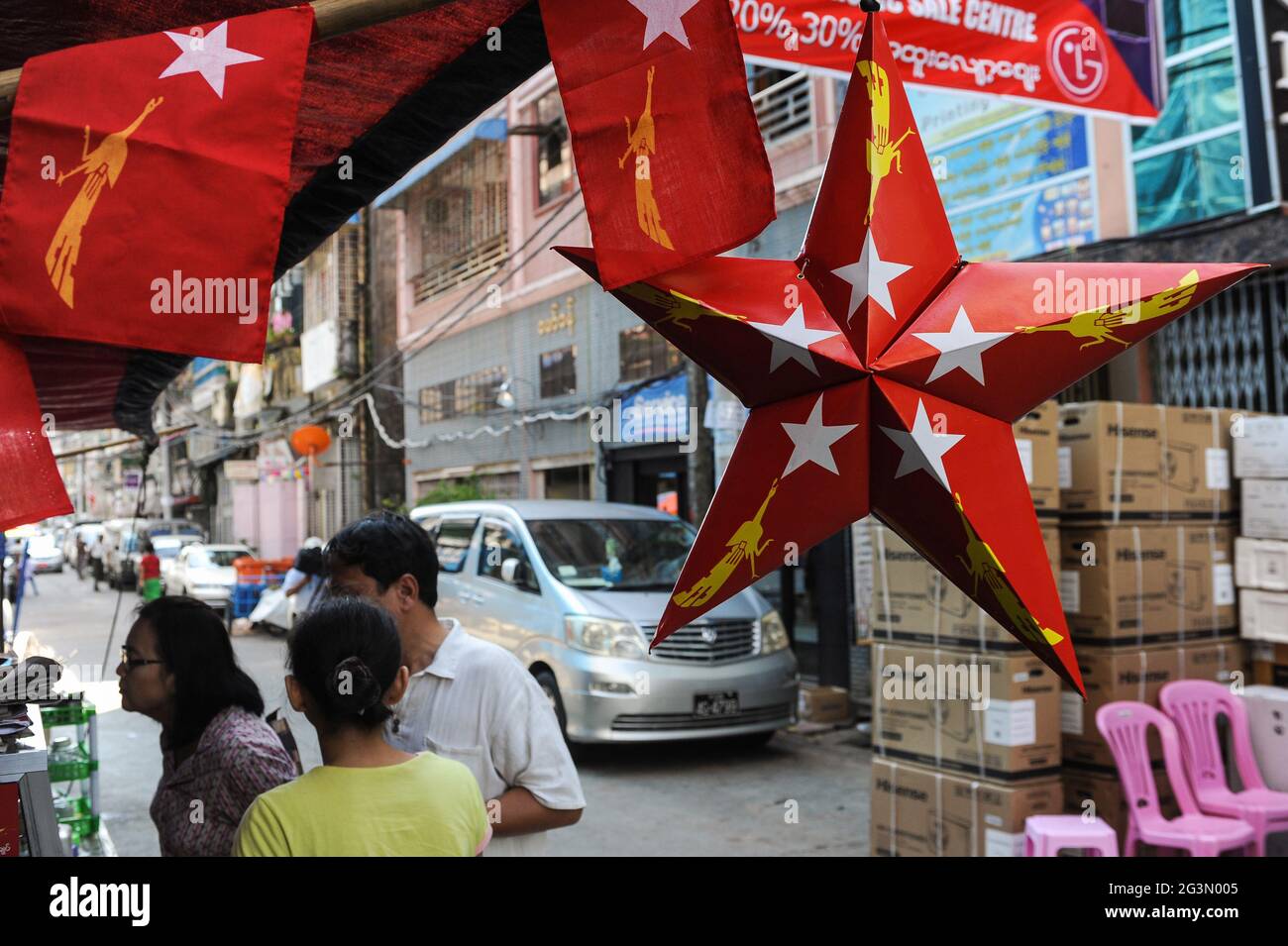'31.10.2015, Yangon, , Myanmar - UNA stella rossa di cartone e bandiere piccole con il logo del partito NLD (Lega Nazionale per la democrazia) appendere su una strada Foto Stock