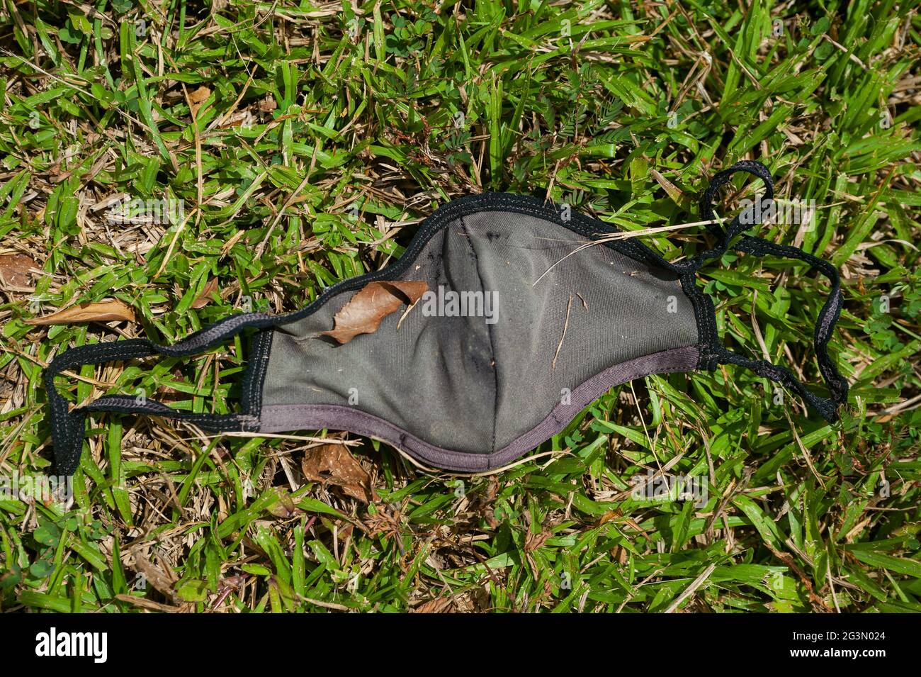 '01.05.2021, Singapore, , Singapore - UN guardiano del bocca usato e scartato per proteggere contro l'infezione con il coronavirus (Covid-19) si trova sul terreno Foto Stock