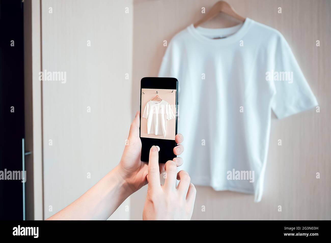La donna sta scattando una foto su uno smartphone di abbigliamento usato per la rivendita o la carità Foto Stock