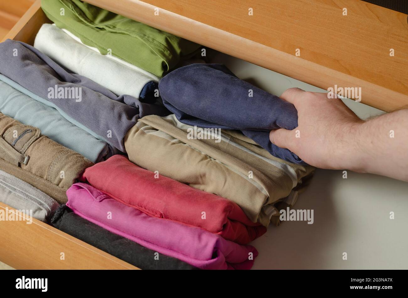 Concept verticale giapponese sistema di stoccaggio abiti. Camicie  multicolore impilate su un ripiano di un comò usando il metodo Konmari di  riassetto. Un uomo è occupato WIT Foto stock - Alamy