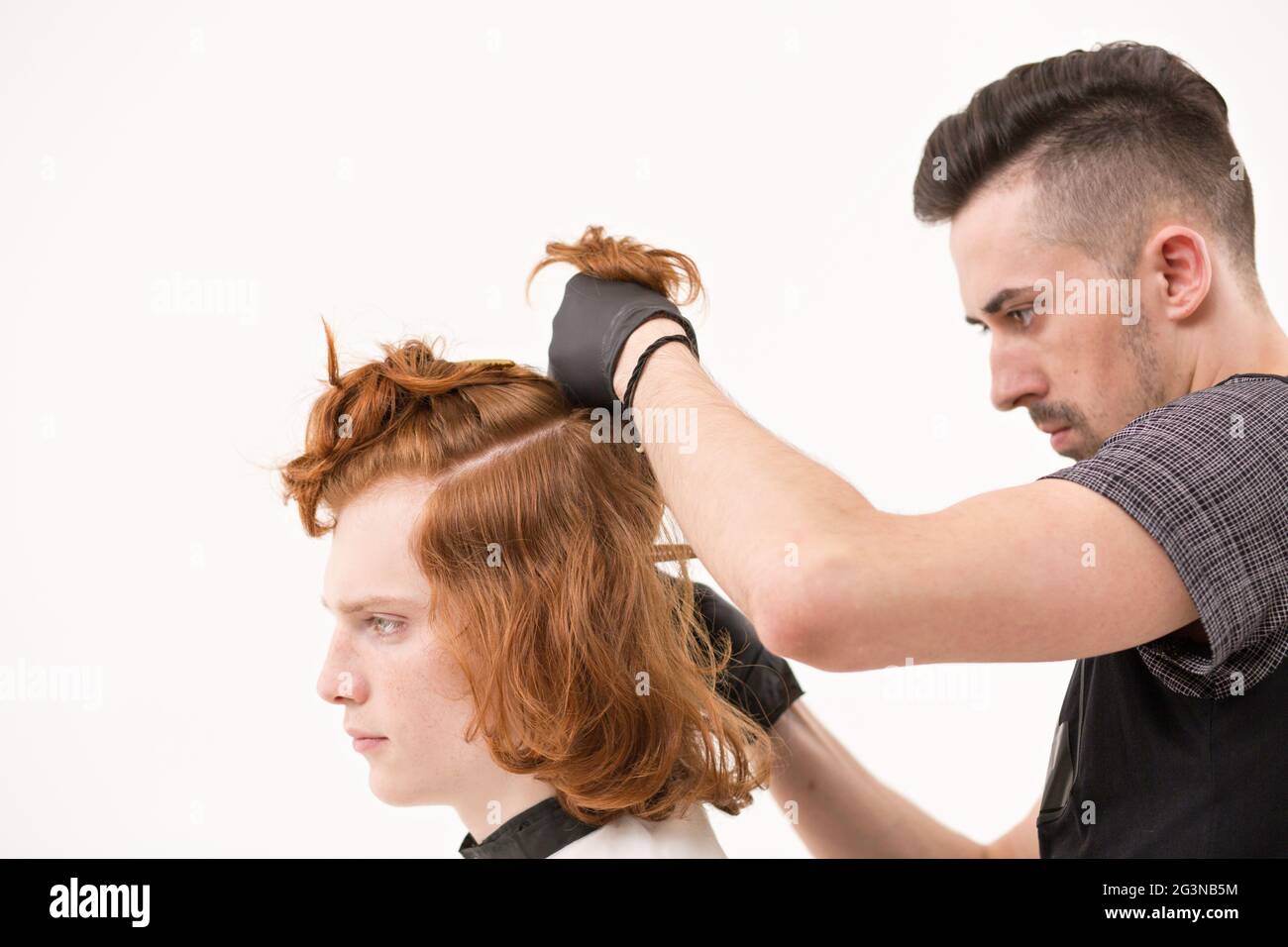 Barbiere ripone un capello del suo cliente con una forcina per capelli Foto Stock