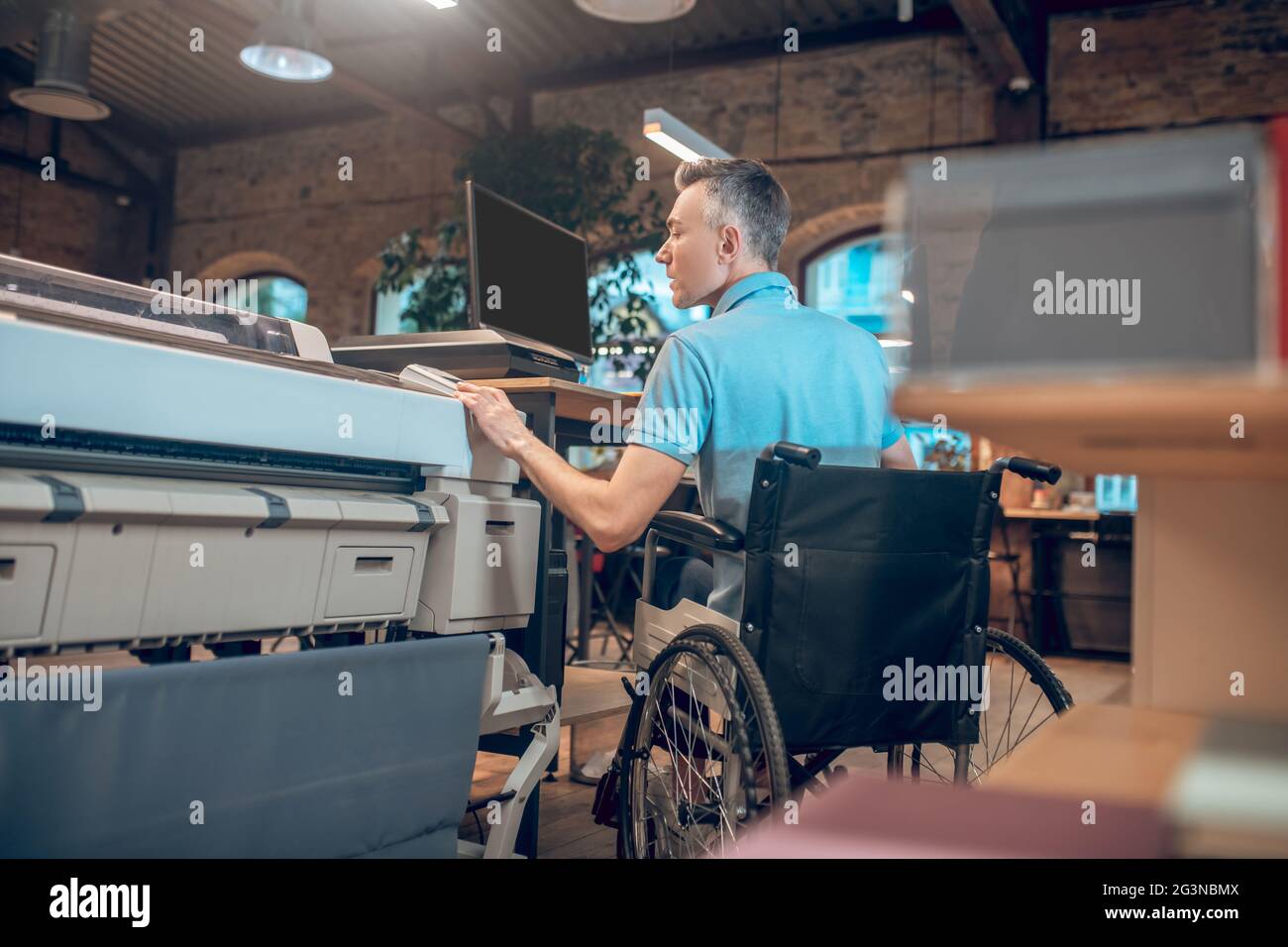 Giovane adulto in copiatrice su sedia a rotelle Foto Stock