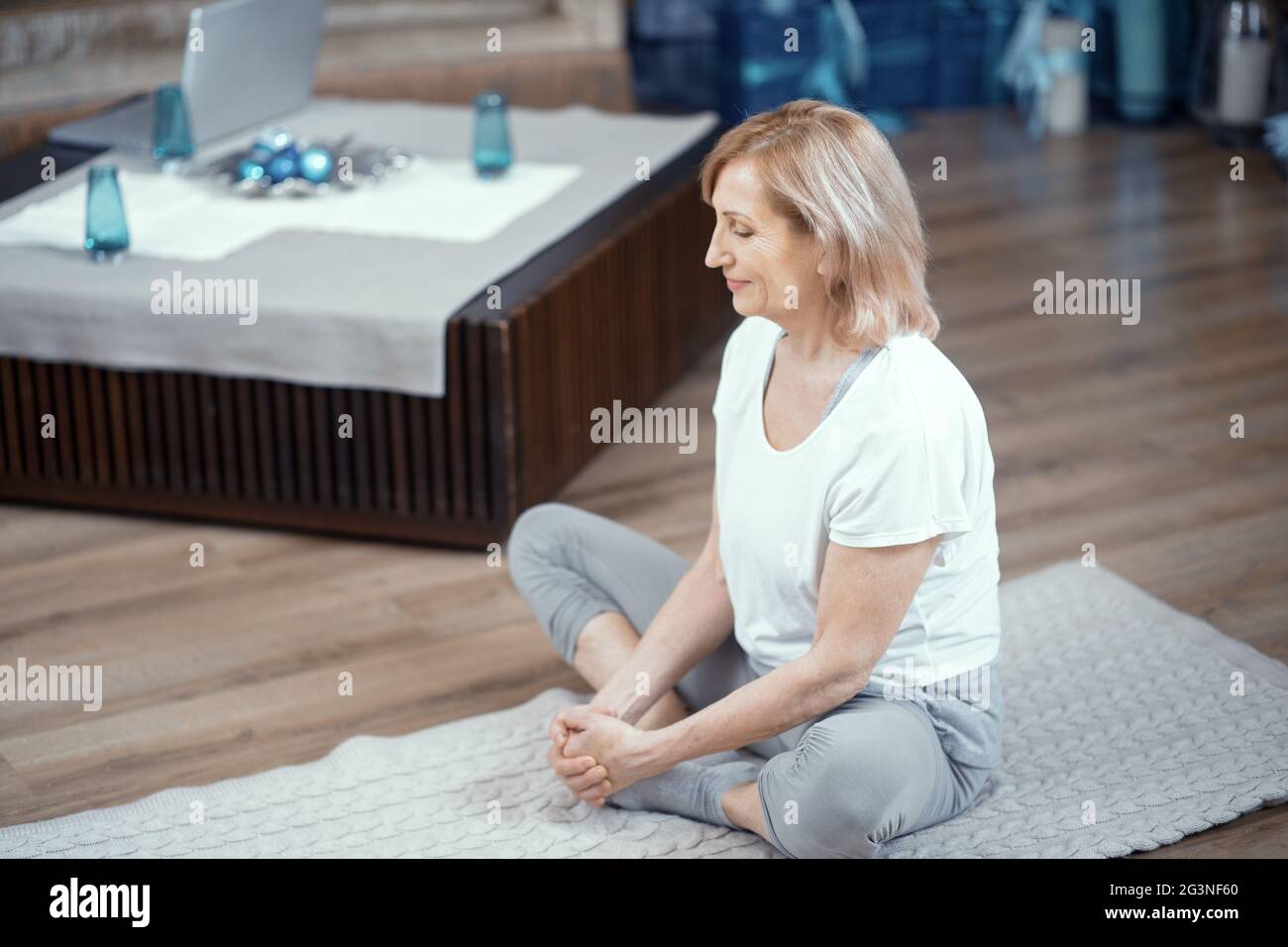 Una donna di età superiore a 50 è fare yoga a casa. Foto Stock