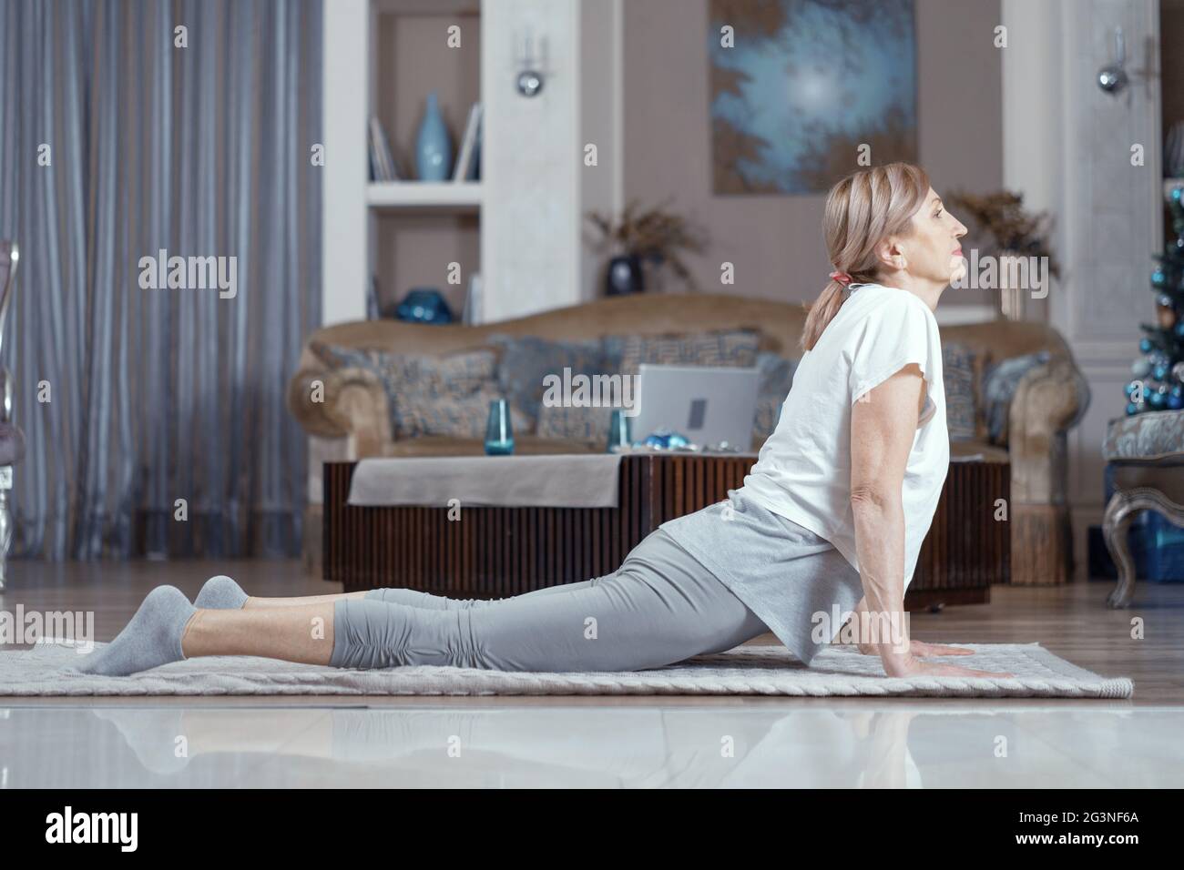 Corsi di Yoga a casa belle donne oltre cinquant'anni. Foto Stock