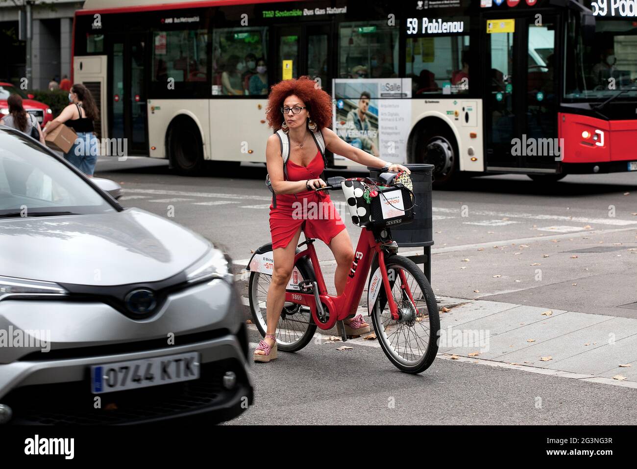Donna in rosso in bicicletta, Barcellona, Spagna. Foto Stock