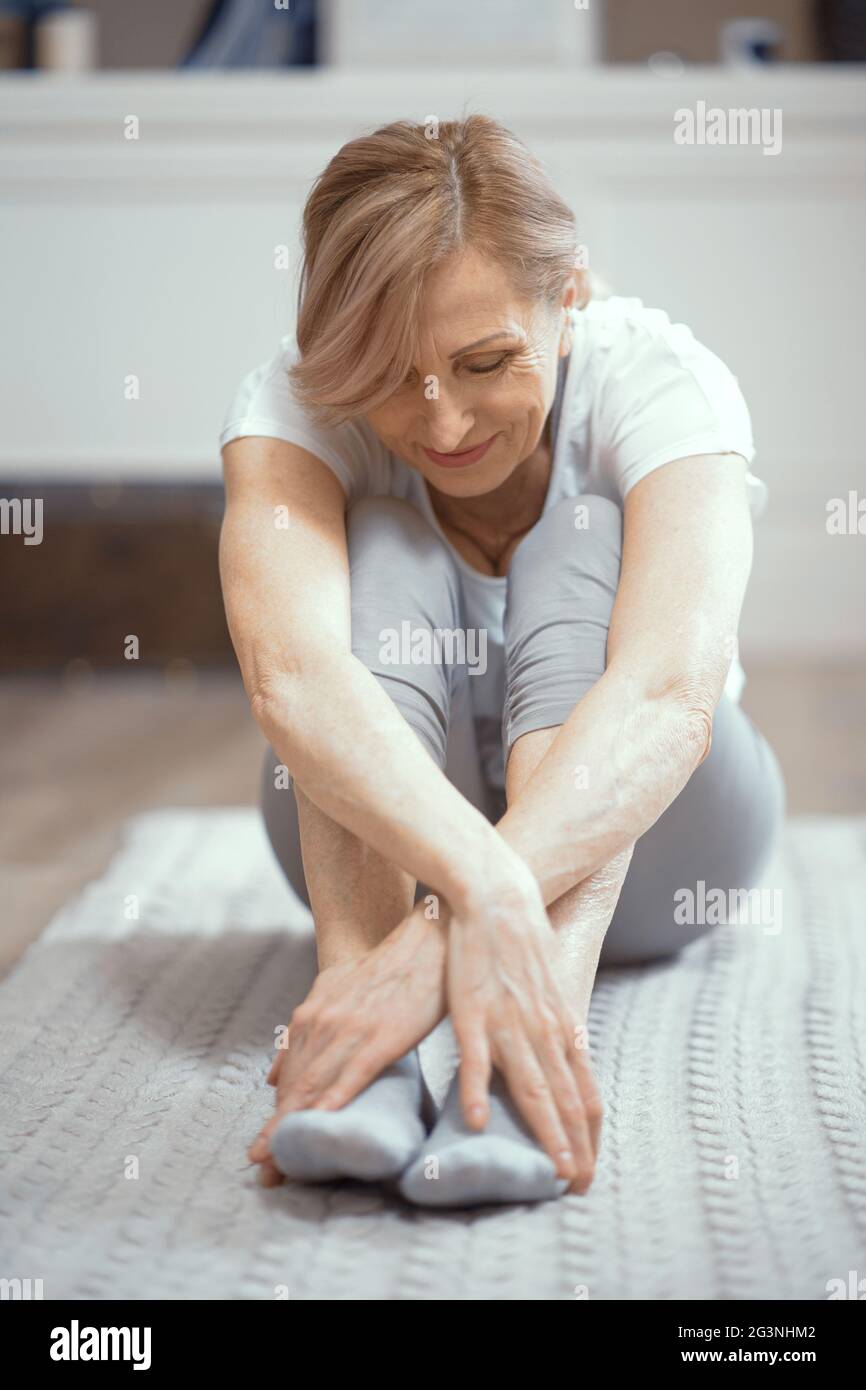 Allegra donna matura rilassante dopo gli esercizi di yoga Foto Stock
