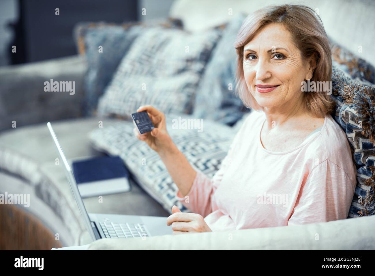 Donna sorridente tiene un notebook che lavora da casa Foto Stock