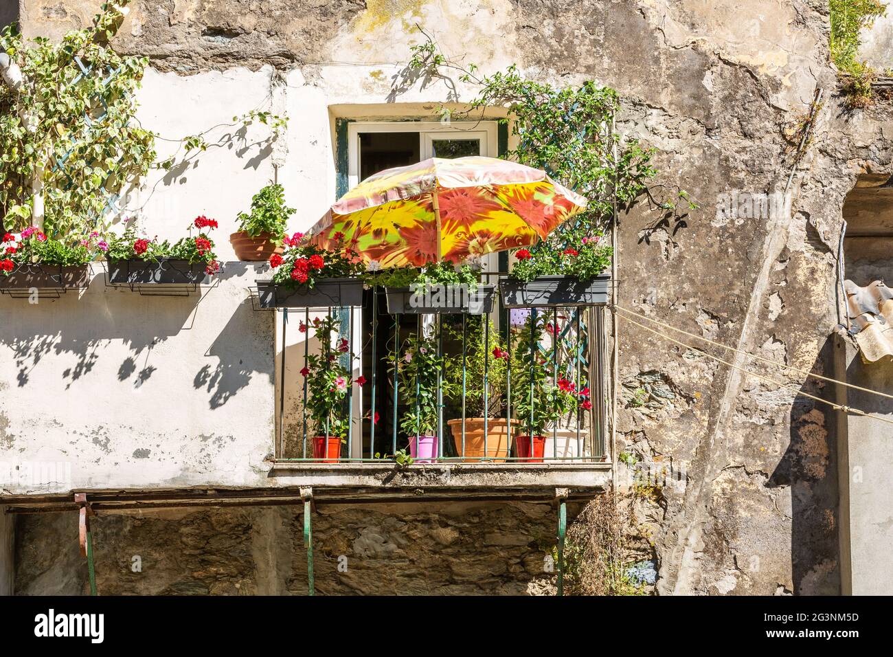 Ombrellone arancione che fornisce qualche ombra su un balcone di una casa nel villaggio di Cervione. Corsica, Francia Foto Stock