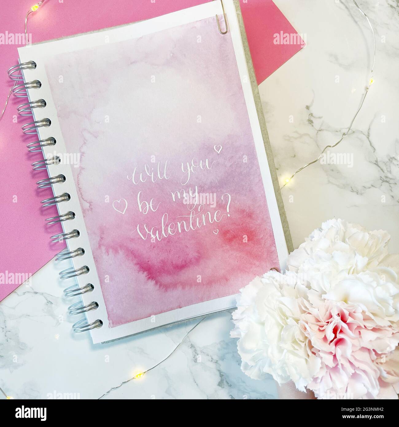 Sarai il mio San Valentino? - inchiostro bianco calligrafia copperplate stile su sfondo rosa acquerello in sketchbook Foto Stock