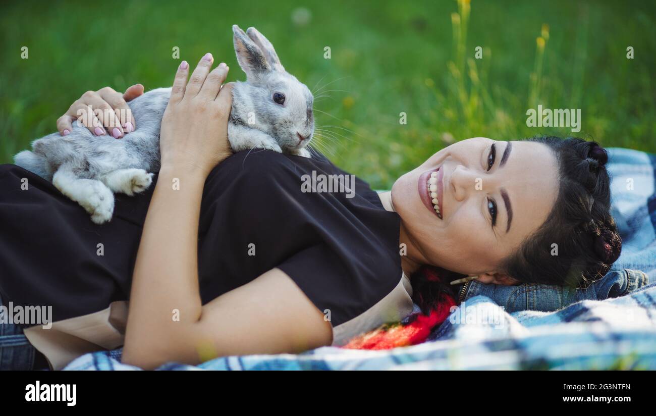 Bella coppia donna asiatica si posa sulla terra e abbracciando un coniglio Foto Stock