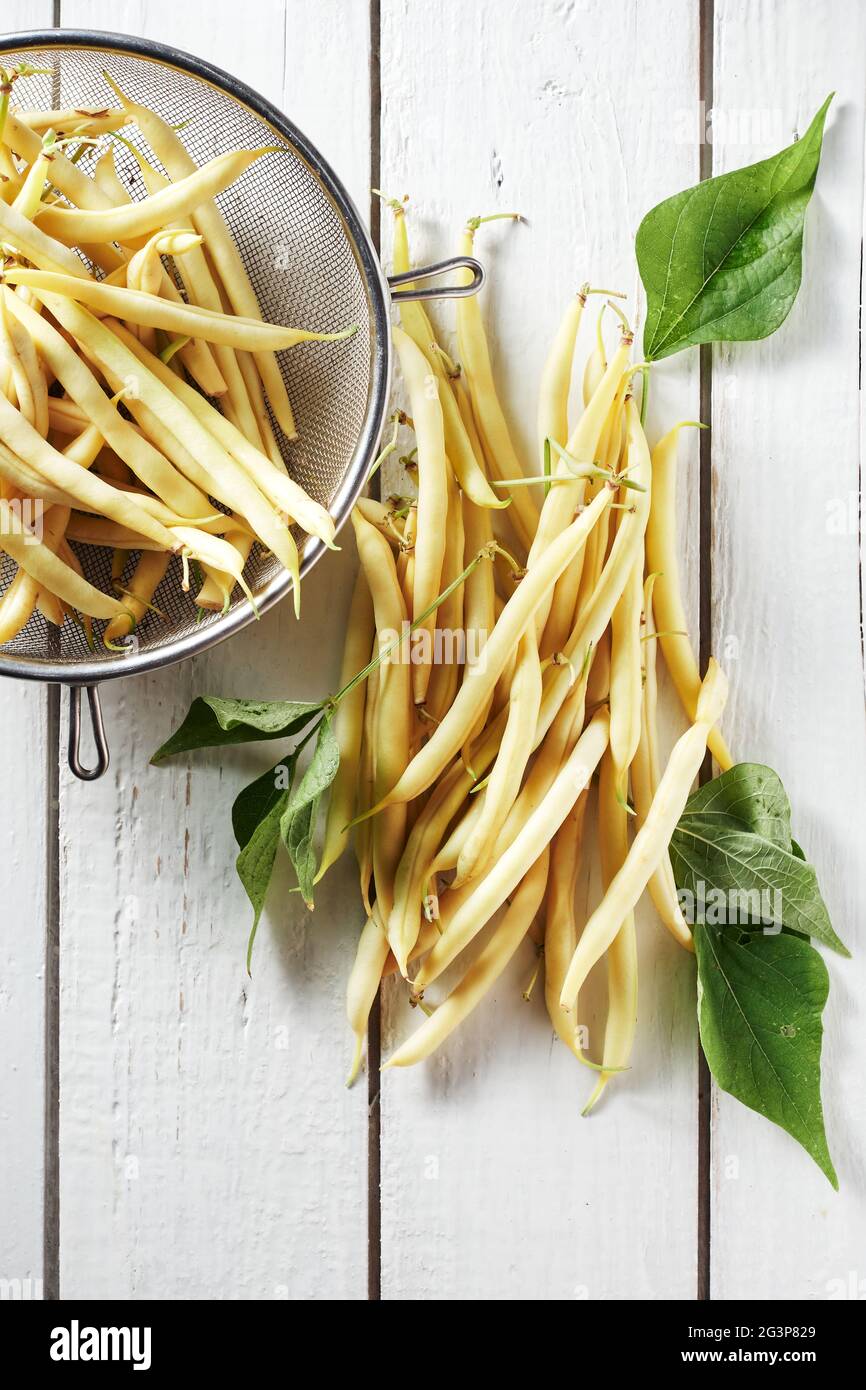 Fagioli di cera gialli su un tavolo di legno bianco. Foto Stock