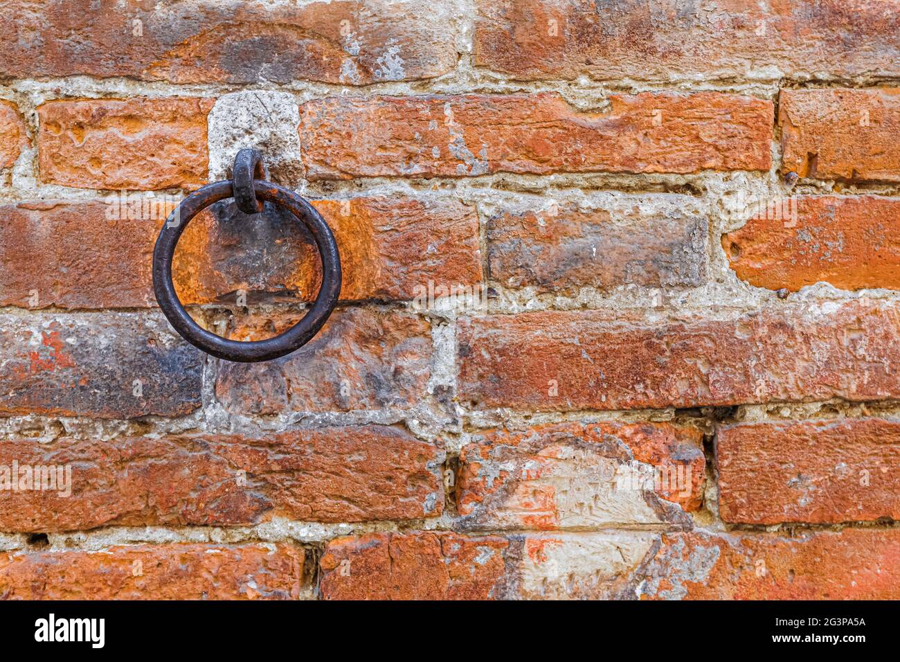 Un anello di metallo arrugginito incorporato in una parete di mattoni rossi. Spazio di copia per il testo Foto Stock