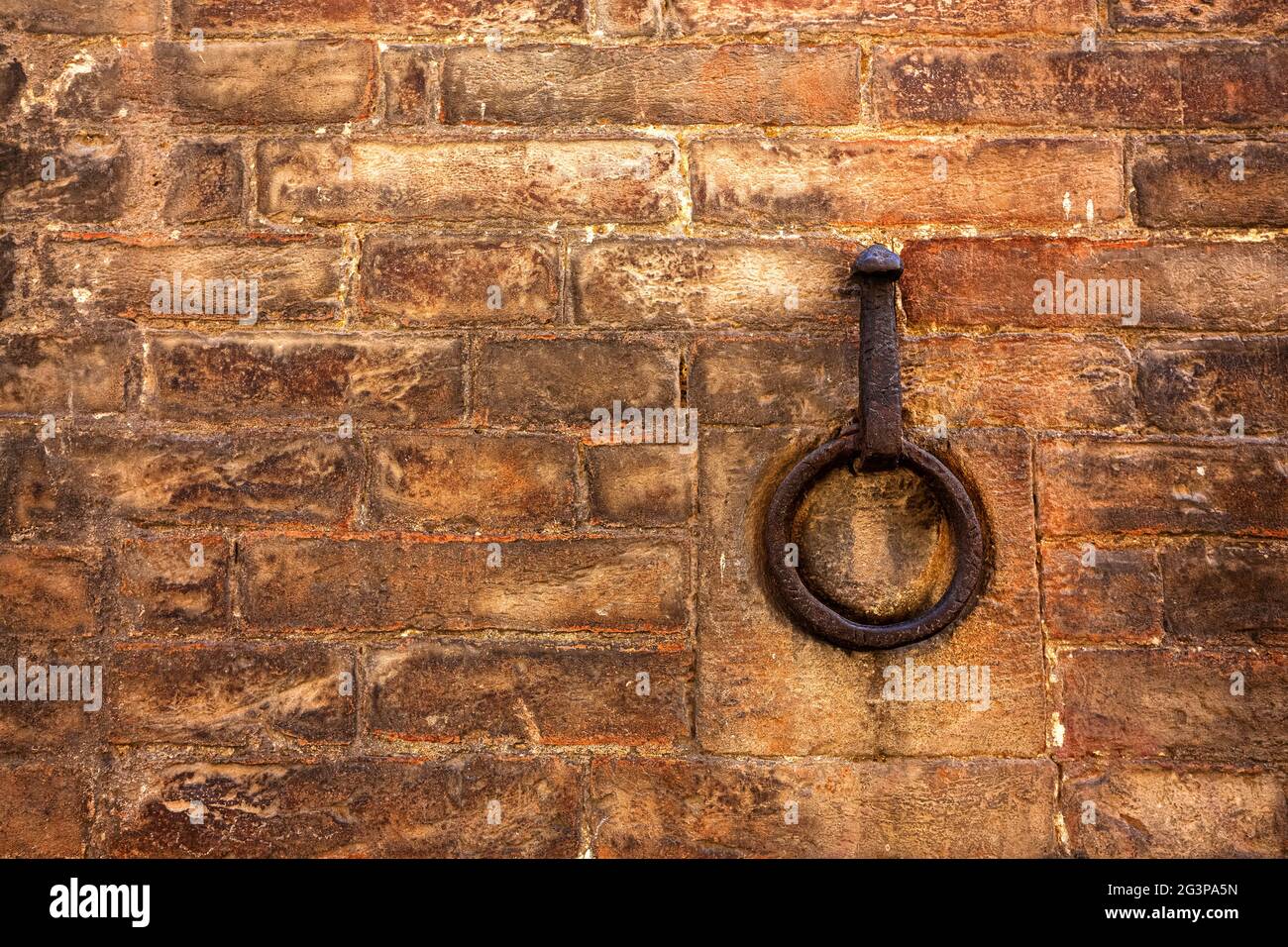 Un anello di metallo arrugginito incorporato in una parete di mattoni rossi. Spazio di copia per il testo Foto Stock