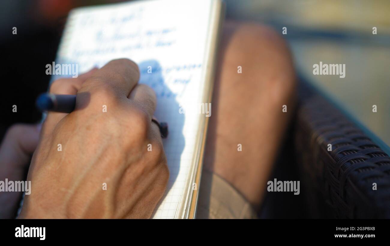 La mano attraente dell'uomo prende le note in un blocco note nei grandi spazi aperti Foto Stock