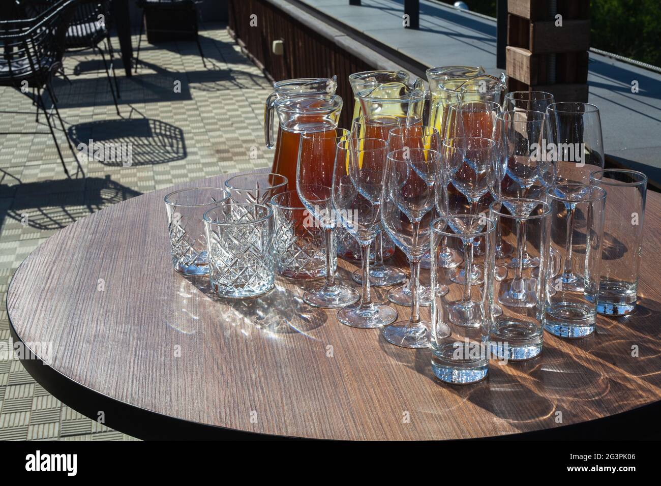 Un set di bicchieri vuoti visualizzati in file e un decanter di limonata fresca o succo per la festa o il matrimonio. Estate rinfrescante frutta-bevanda da mele Foto Stock