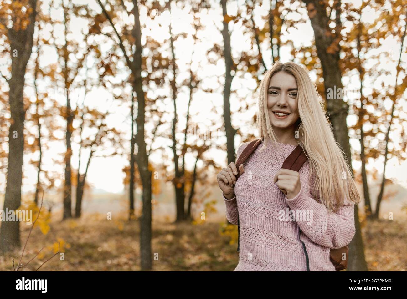Donna Blonde Traveler posa sul retro della foresta d'autunno Foto Stock