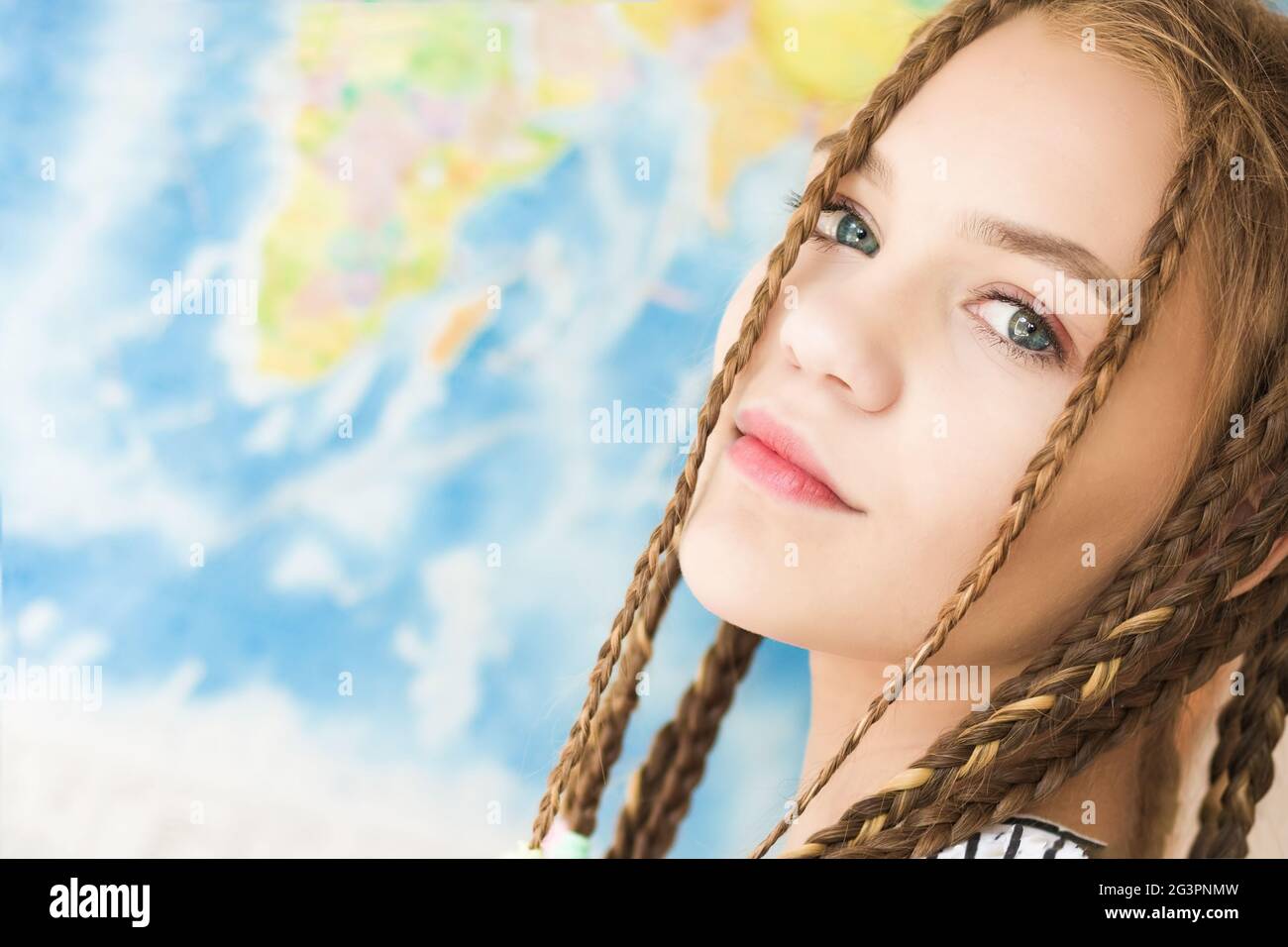 Ritratto di una bella ragazza faccia da vicino su uno sfondo di mappa del mondo. Luce naturale soffusa Foto Stock