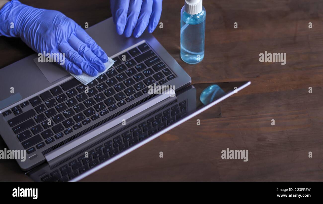 Disinfezione della tastiera di un computer. I guanti a mano eseguono la lavorazione antisettica delle superfici di lavoro. Misure preventive necessarie Foto Stock