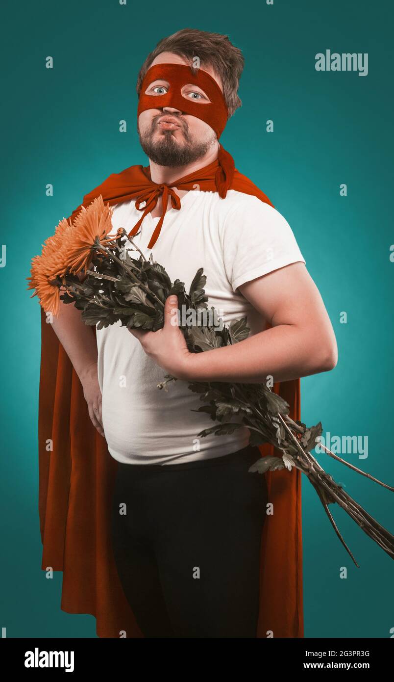 Super eroe innamorato di un mazzo di fiori per il suo amante. Uomo in costume Superhero con un bouquet di crisantemi folde Foto Stock