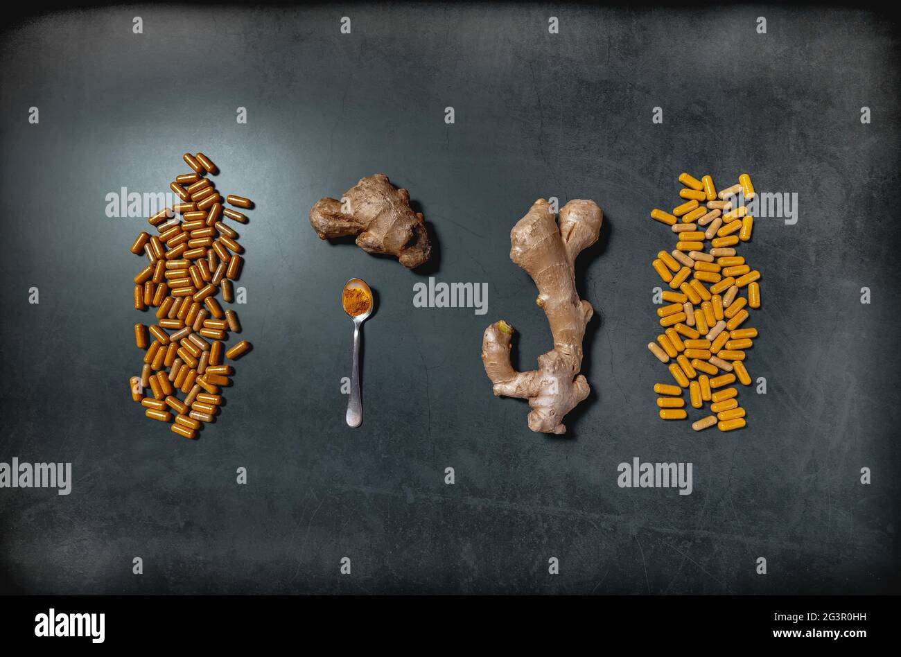 La fotografia di un prodotto scuro a posa piatta di una radice di zenzero e di capsule di polvere su un pannello di cemento nero. Medicina naturale e supplemento di erbe terapia conce Foto Stock