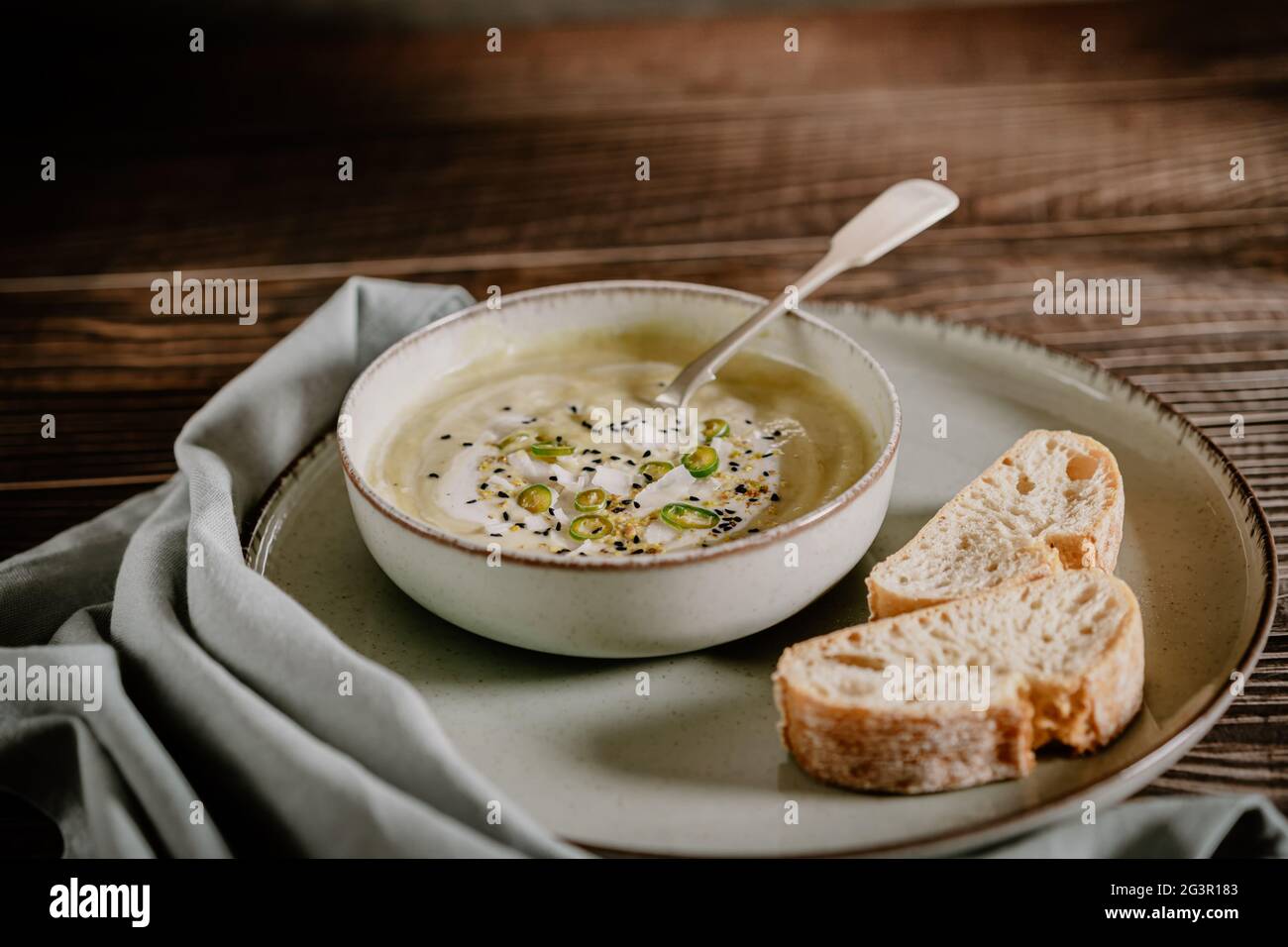 Fotografia alimentare di una zuppa di crema di zucca vegana e pane con fuoco selettivo. Ricetta di verdure. Una purea autunnale di prodotti di stagione su una linguetta di legno Foto Stock