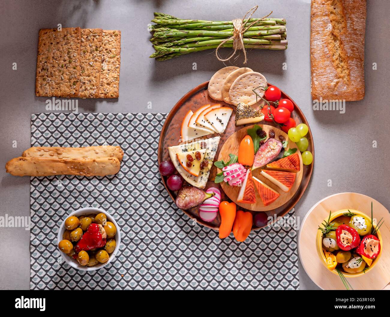 Fotografia di piatti di formaggio a tavola con olive, cracker, pomodori ciliegini, asparagi e peperoni ripieni di formaggio cremoso. Summe Mediterraneo Foto Stock
