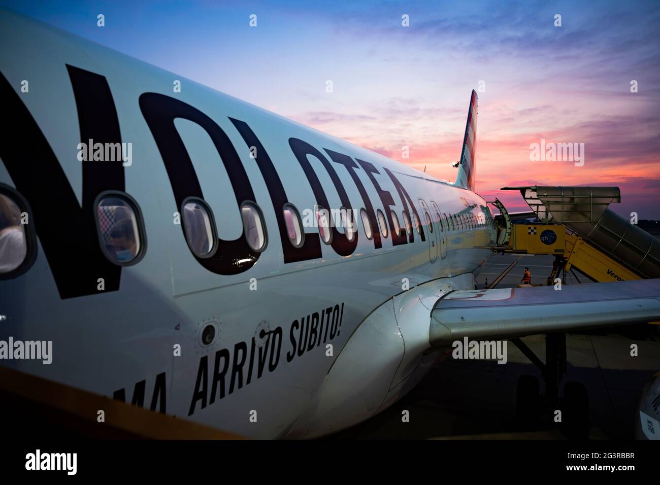 Aereo commerciale pronto ad imbarcarsi sui passeggeri dall'aeroporto di Verona durante un tramonto mozzafiato. Foto Stock