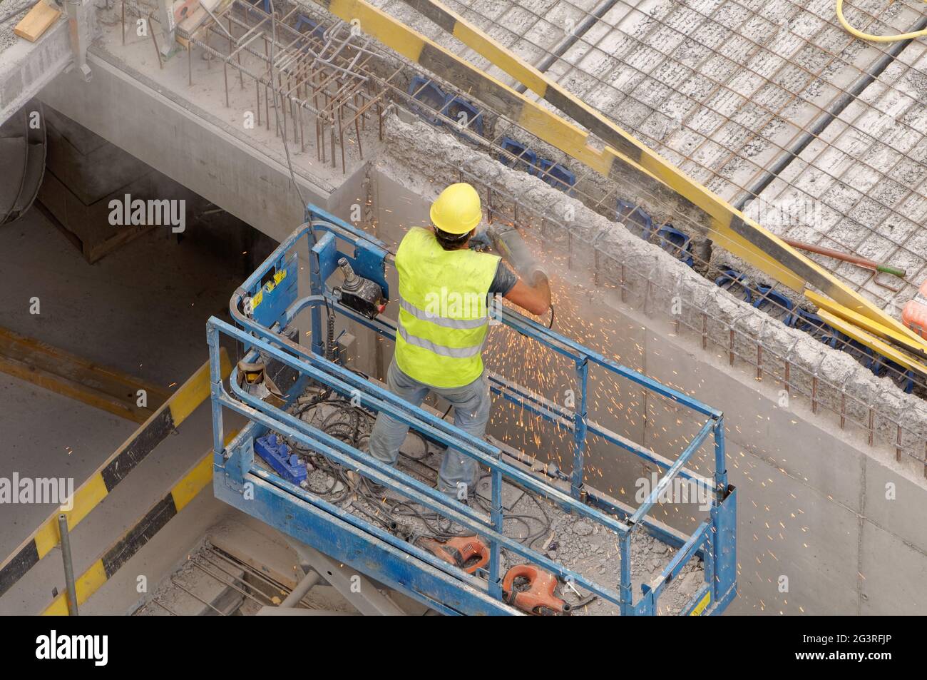 Operatore in ascensore che utilizza un macinacaffè in un cantiere (edificio) protetto da un casco Foto Stock