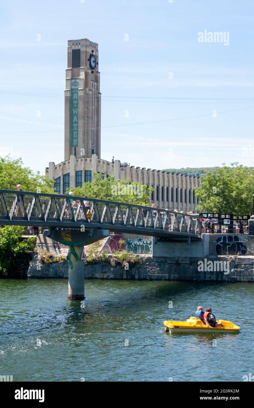 Un pedalo passa sotto il ponte pedonale del mercato dell'acqua, con il famoso mercato di Montreal sullo sfondo Foto Stock