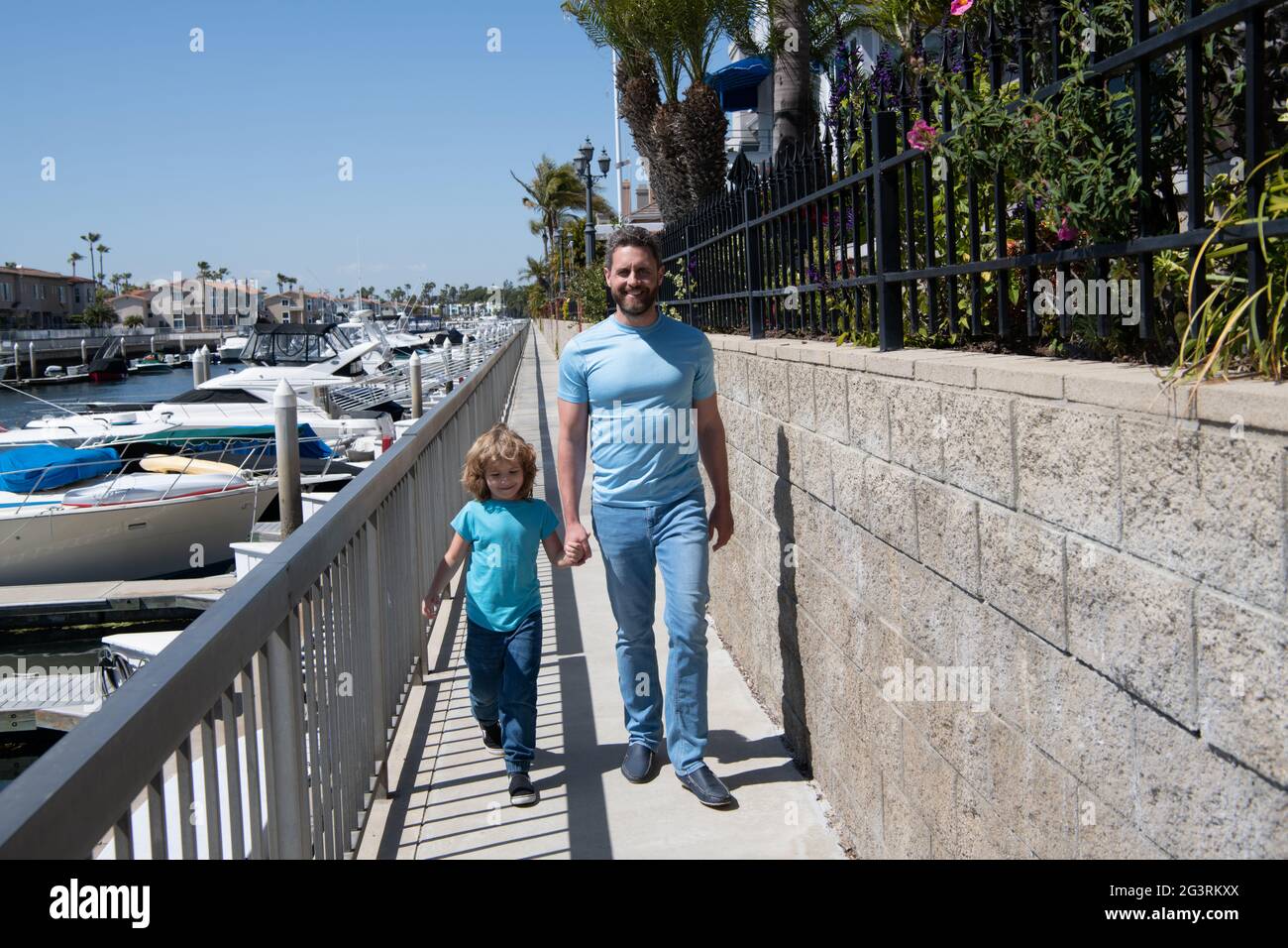 Camminare insieme. Padre e figlio Promenade tenendo le mani. L'uomo e il bambino si godono una piacevole passeggiata Foto Stock