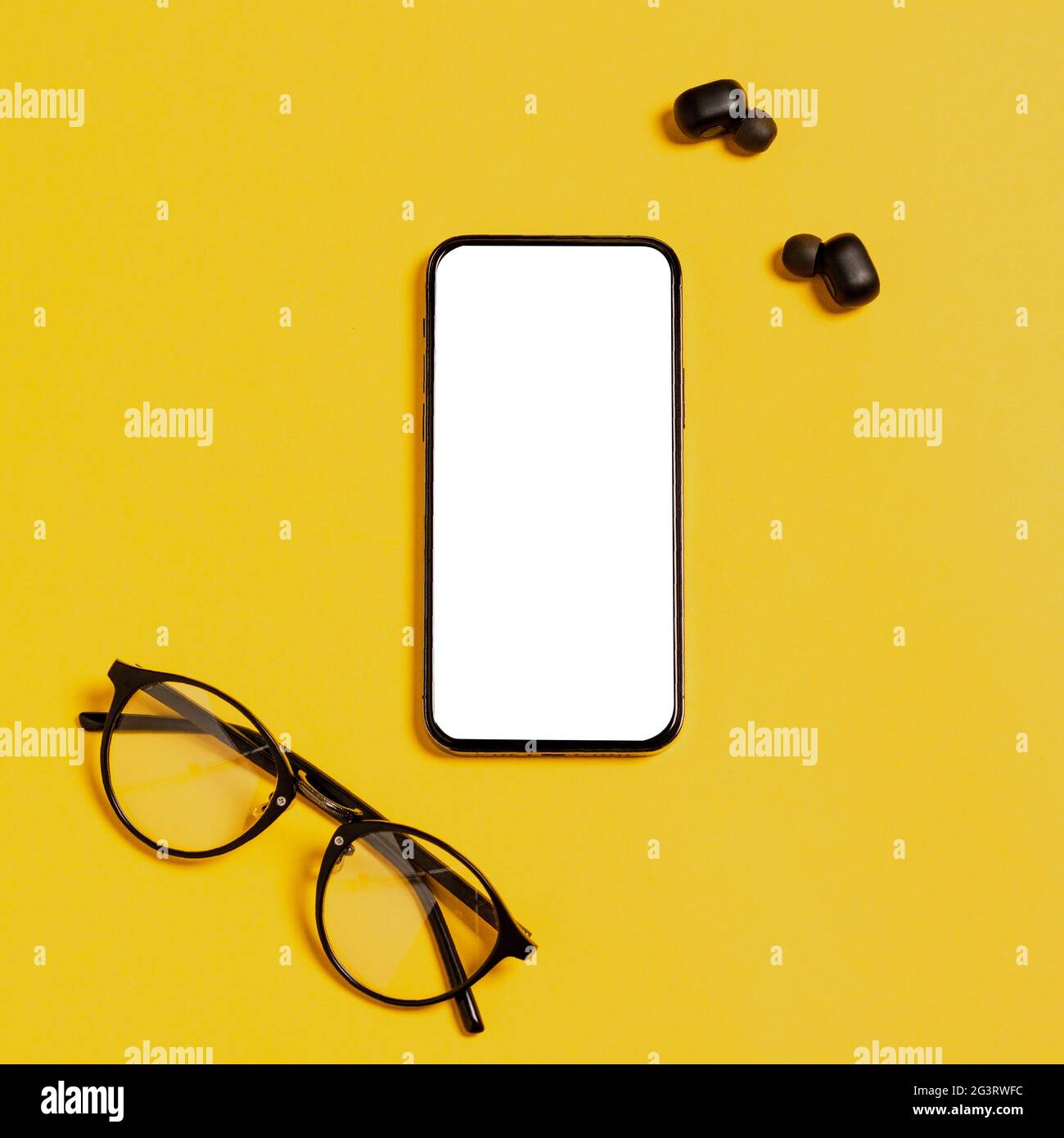 Mockup per smartphone con display bianco vuoto per annunci di applicazioni mobili moderni. Cuffie wireless, occhiali, sfondo giallo. App per social media Foto Stock