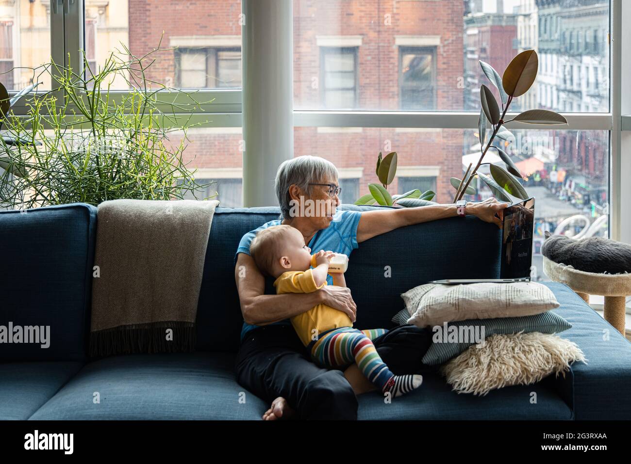 Donna anziana che tiene la nipote del toddler che beve da un biberon Foto Stock