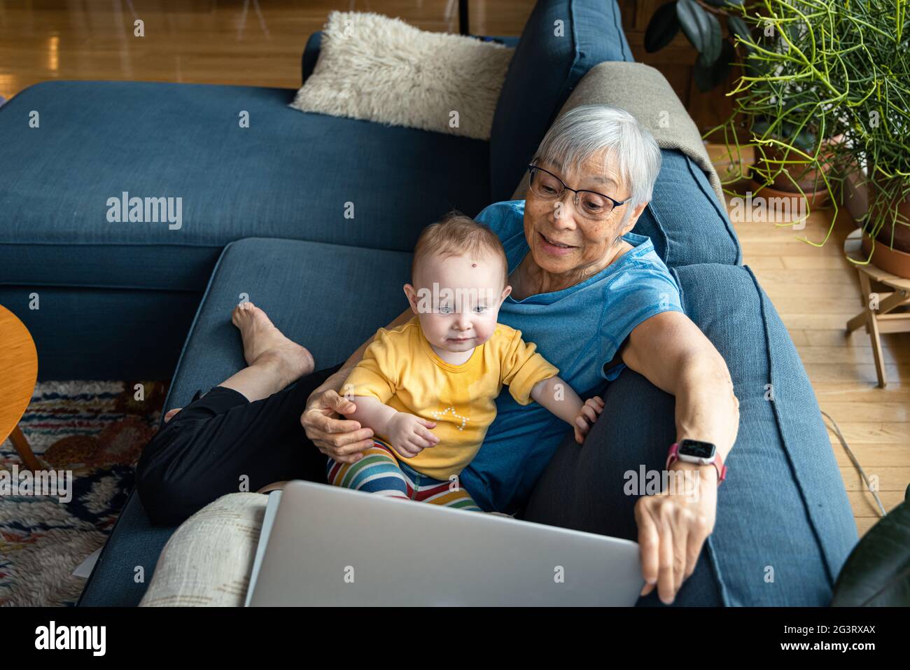 Nonno seduto con la nipote utilizzando il laptop per videochiamare Foto Stock