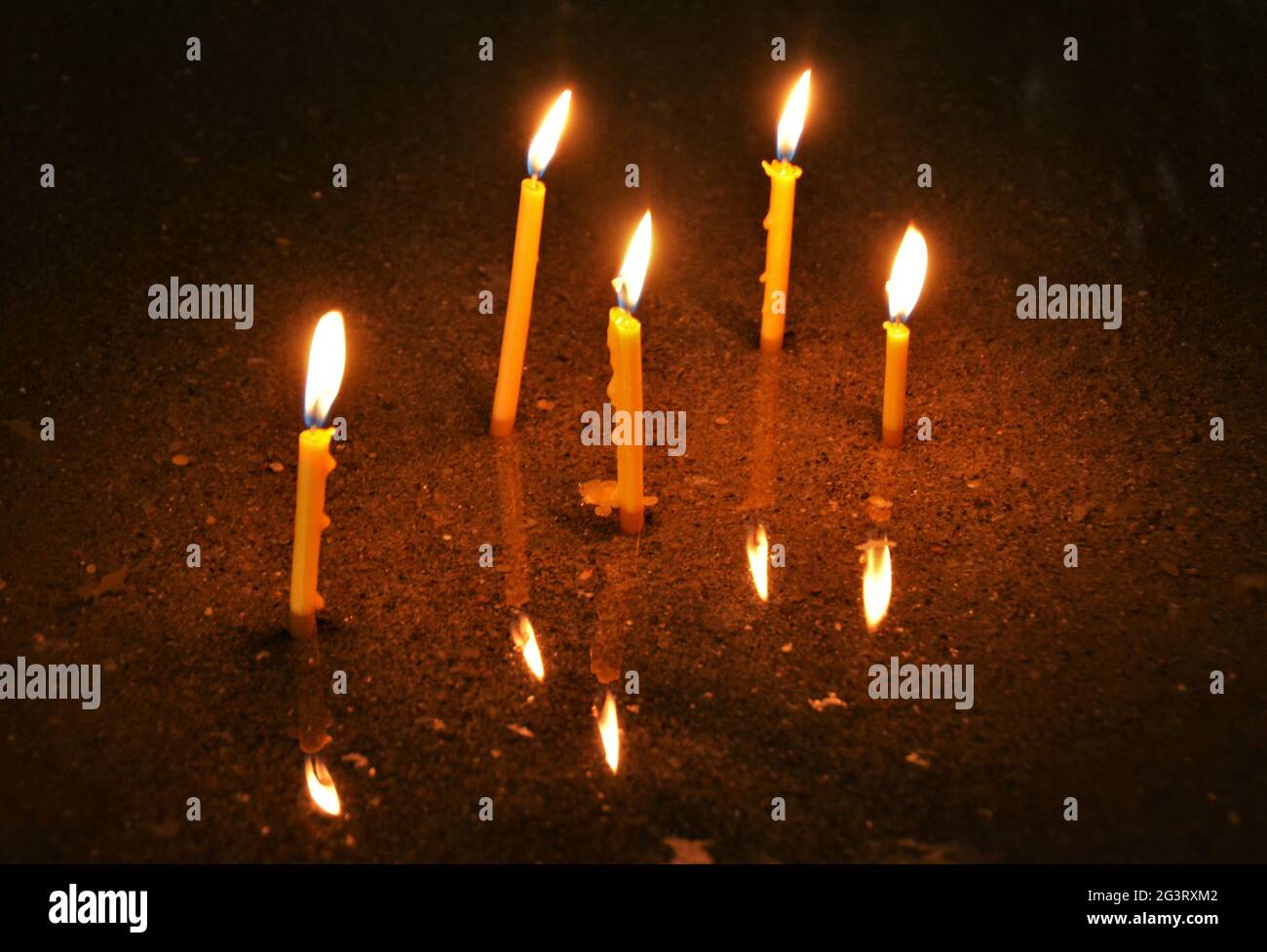 Alto angolo di candele brucianti e riflessione in una chiesa Foto Stock