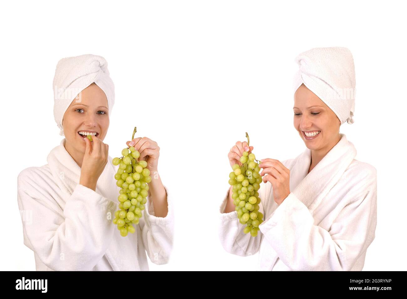 due giovani donne in accappatoi bianchi che mangiano l'uva Foto Stock