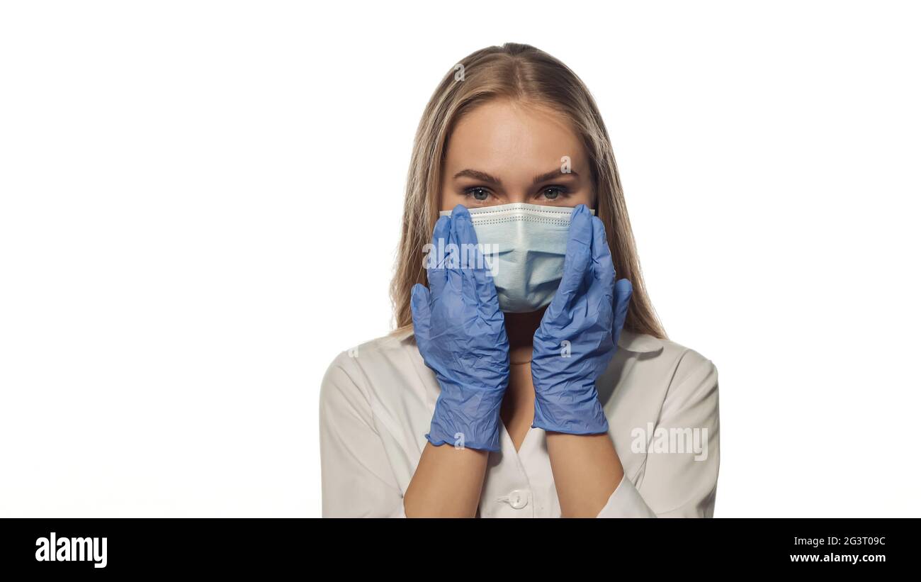 Giovane infermiera con capelli lunghi in maschera che guarda dritto. Foto Stock