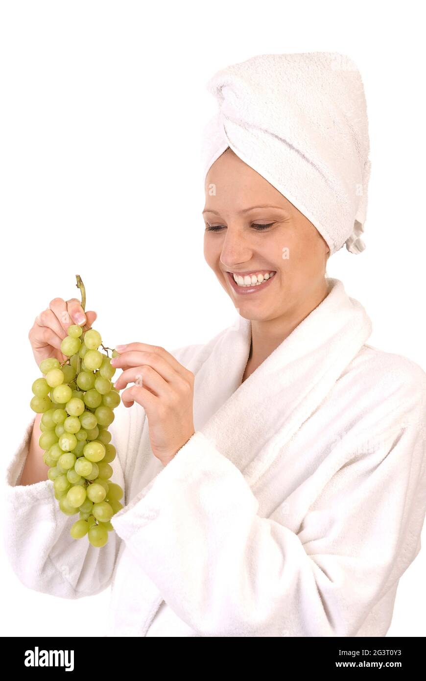 giovane donna in accappatoio bianco che mangia uva Foto Stock