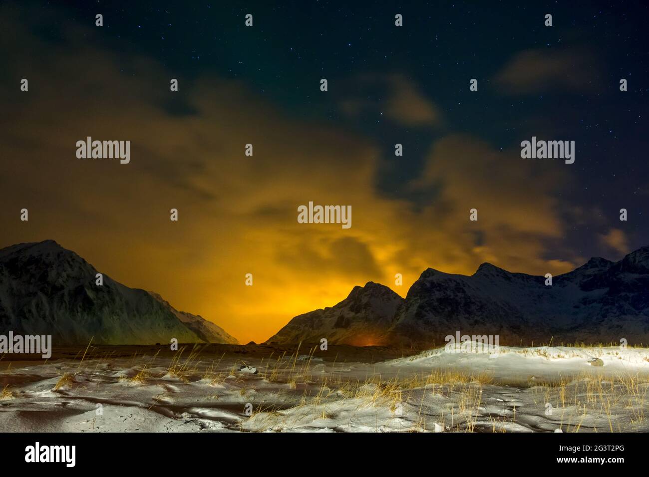 Erba coperta di neve e Glow oltre le montagne Foto Stock