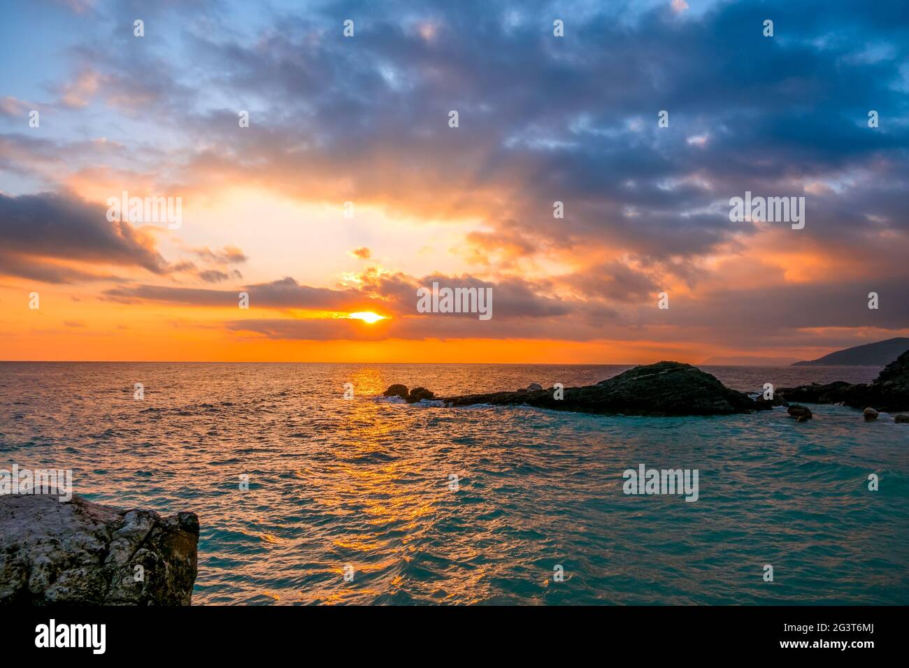 Sea Dawn e Sun Rays sulla Rocky Shore Foto Stock