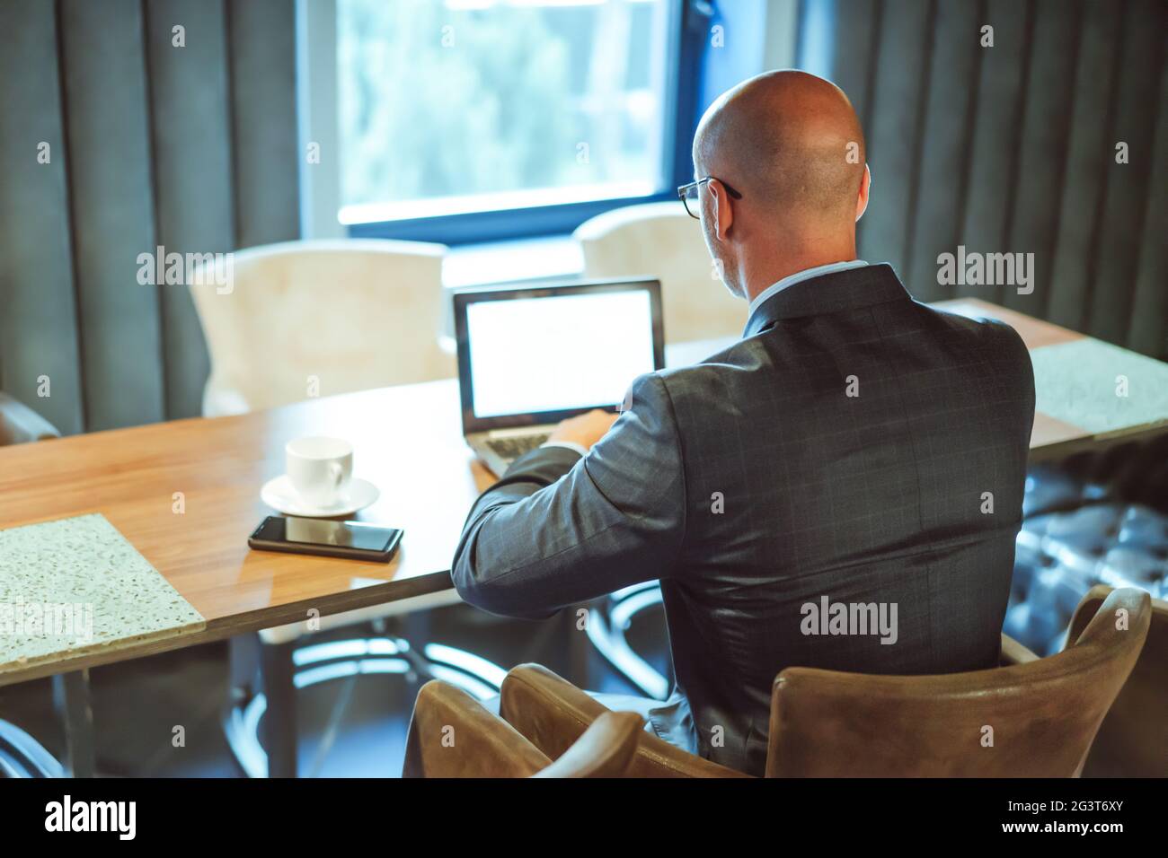 Uomo d'affari che utilizza la tecnologia wireless digitale. Vista posteriore di un uomo caucasico di successo che lavora con un computer portatile sul luogo di lavoro A. Foto Stock