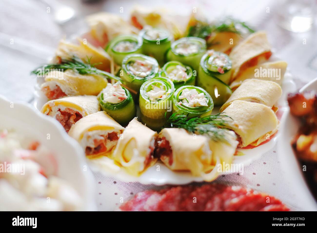 Sul tavolo festivo c'è un piatto con un delizioso spuntino. Panini con pesce e cetrioli. Foto Stock