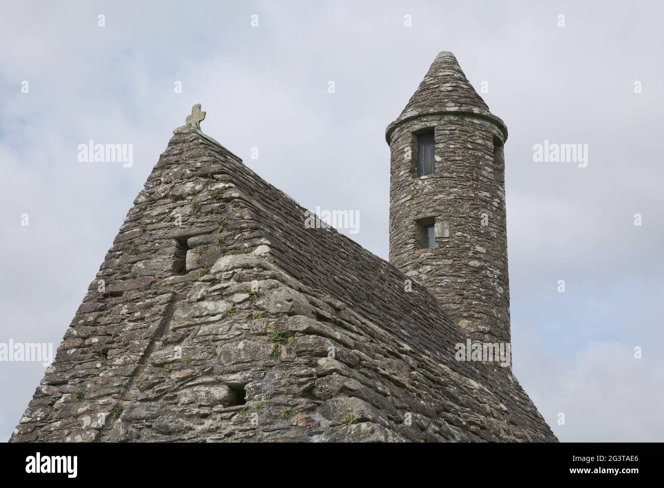 Torre rotonda in pietra e alcune rovine di un insediamento monastico originariamente costruito nel 6 ° secolo nella valle di Glendalough, County Wick Foto Stock