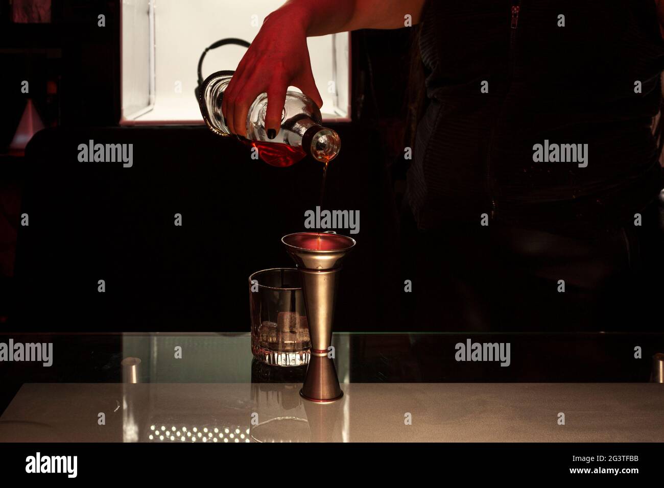 Bar tenera che serve sapientemente whisky dalla bottiglia al bicchiere dietro il bar di un nightclub a Città del Messico Foto Stock