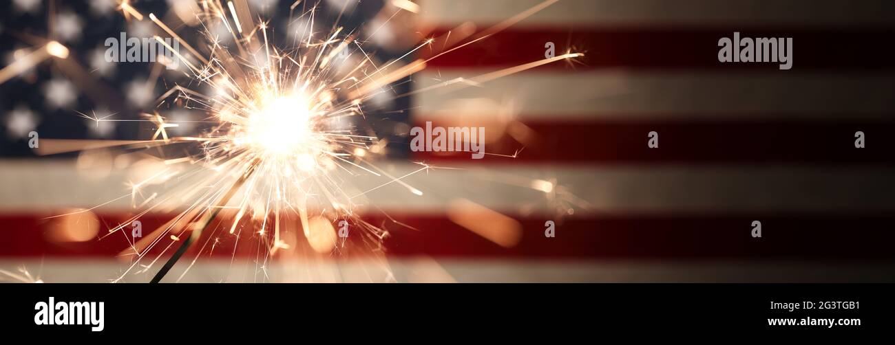 Scintille che scendono da un scintillante acceso davanti alla bandiera americana per la celebrazione patriottica del 4 luglio. Foto Stock