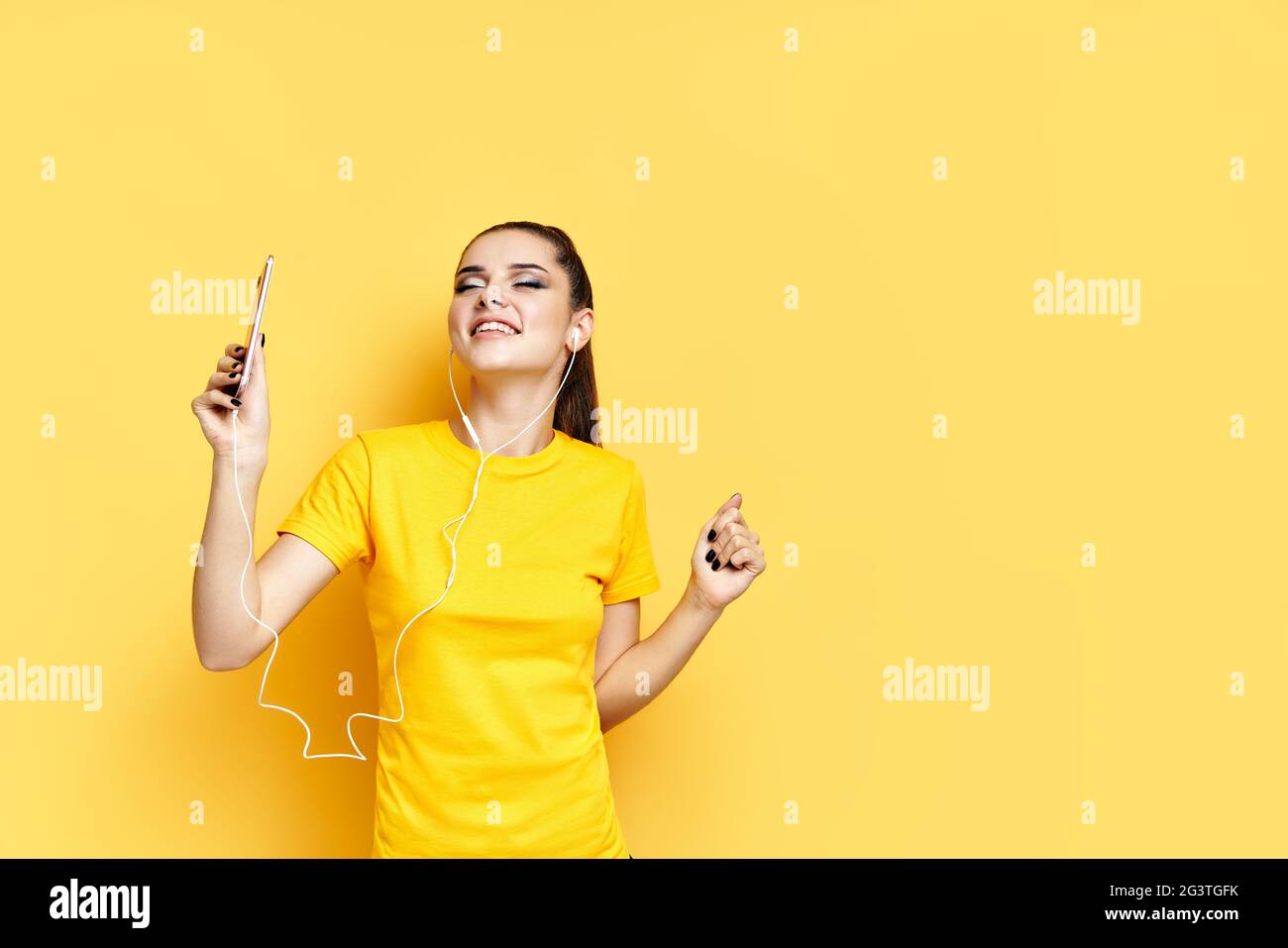 Giovane donna allegra che ascolta la musica con le cuffie e balla goditi le canzoni preferite Foto Stock